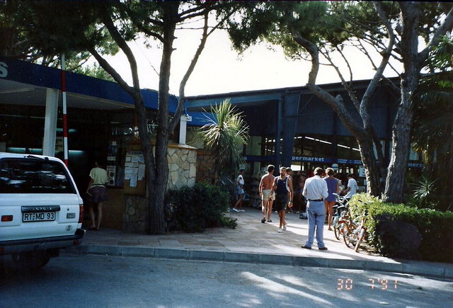 Fotografia de l'entrada del càmping Albatros de Gavà Mar (a l'esquerra) i del seu supermercat (a la dreta) (30 de Juliol de 1991)